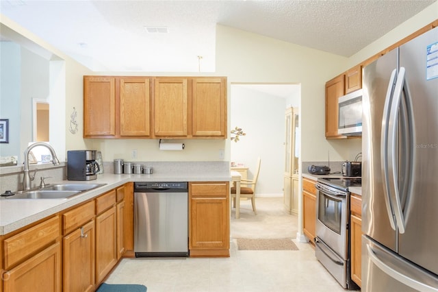 kitchen featuring lofted ceiling, sink, stainless steel appliances, and a textured ceiling