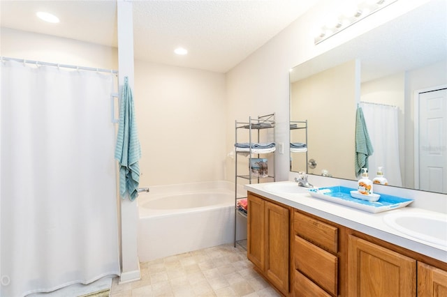 bathroom featuring vanity, a bathing tub, and a textured ceiling