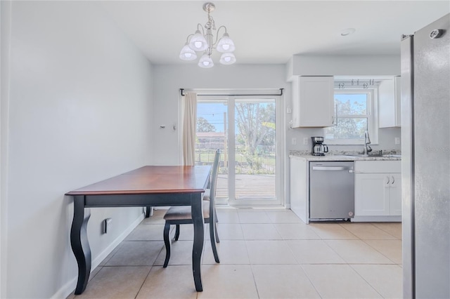 kitchen featuring sink, white cabinetry, light stone counters, decorative light fixtures, and stainless steel dishwasher