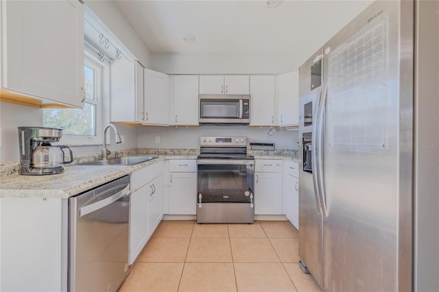 kitchen featuring stainless steel appliances, sink, light tile patterned floors, and white cabinets