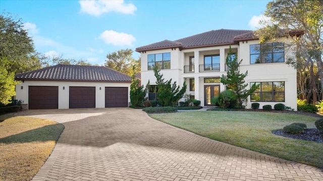 mediterranean / spanish-style home featuring a garage, a balcony, and a front lawn