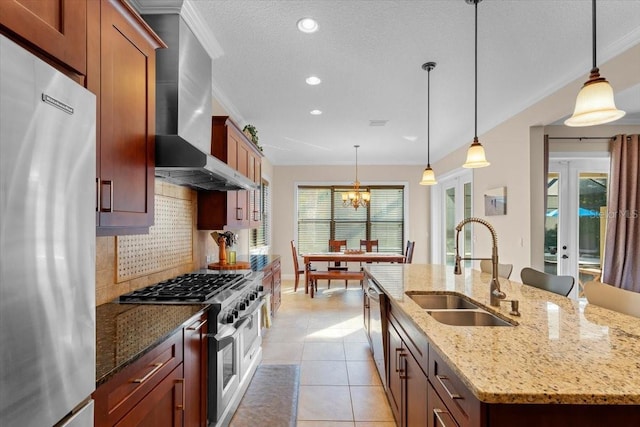 kitchen with sink, appliances with stainless steel finishes, light stone countertops, a center island with sink, and exhaust hood