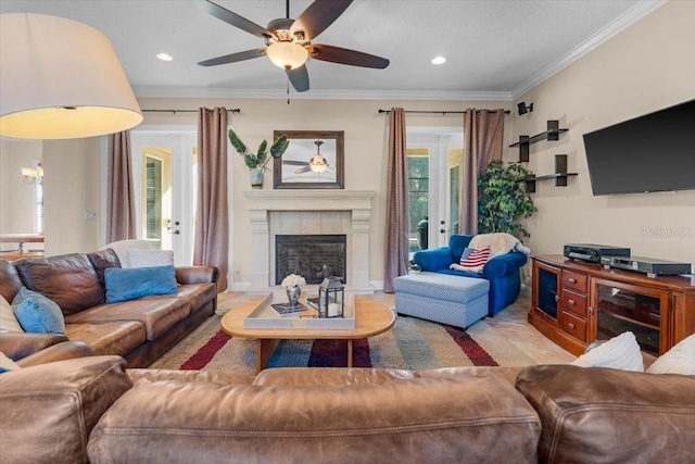 living room with french doors, ceiling fan, ornamental molding, and a tile fireplace