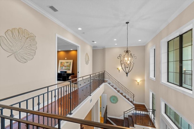 stairway featuring ornamental molding and a chandelier