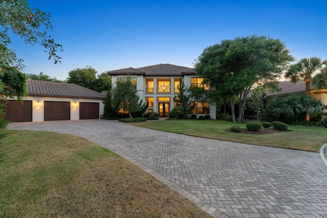 mediterranean / spanish-style house featuring french doors, a yard, and a garage