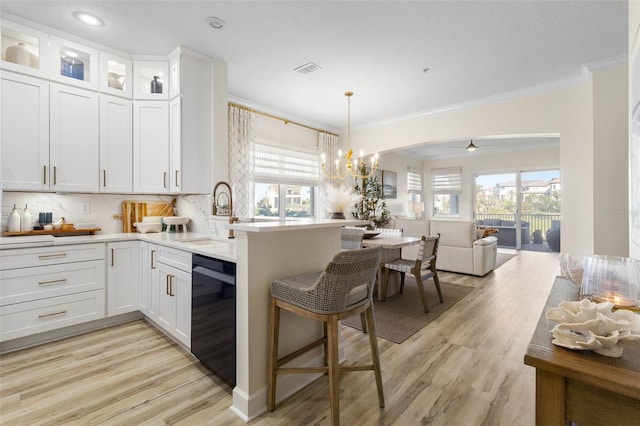 kitchen with decorative light fixtures, dishwasher, sink, and white cabinets