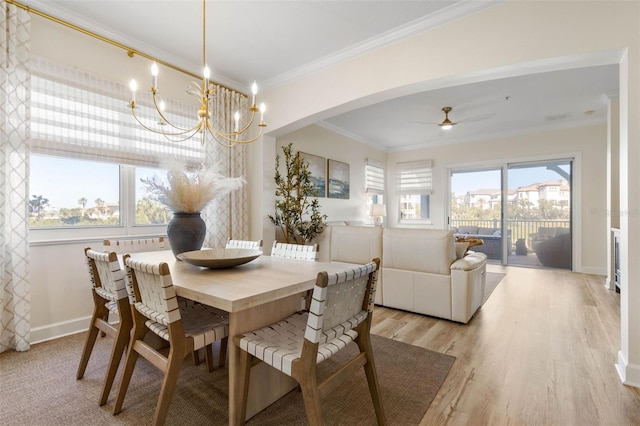 dining space with ceiling fan with notable chandelier, ornamental molding, and light wood-type flooring