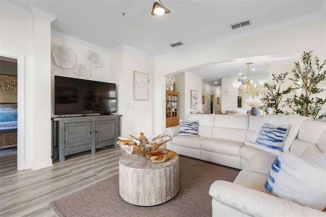 living room with wood-type flooring, ornamental molding, and a chandelier