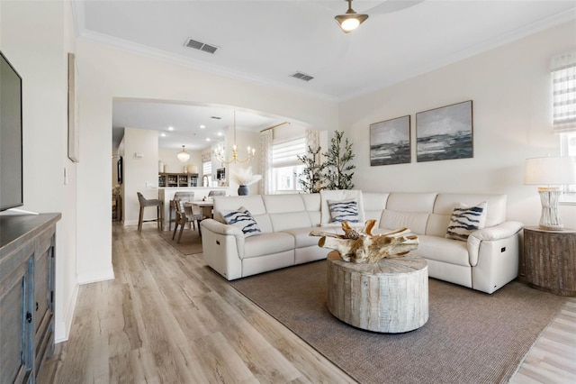 living room with an inviting chandelier, ornamental molding, and light hardwood / wood-style flooring