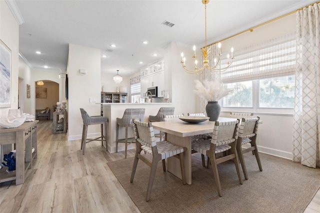 dining space featuring ornamental molding, a notable chandelier, and light hardwood / wood-style flooring