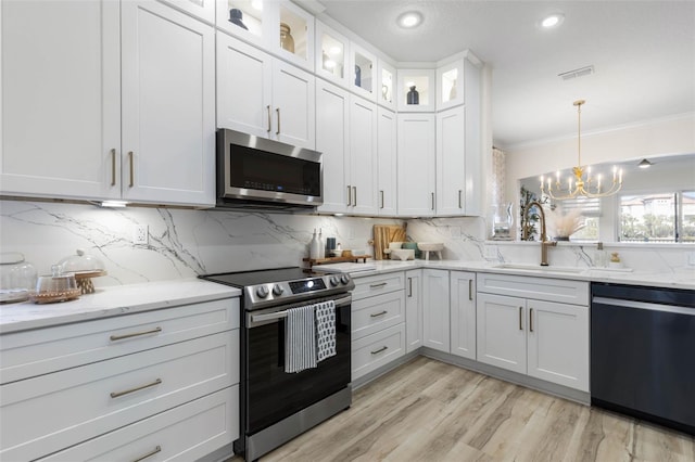 kitchen featuring sink, hanging light fixtures, stainless steel appliances, light stone counters, and white cabinets