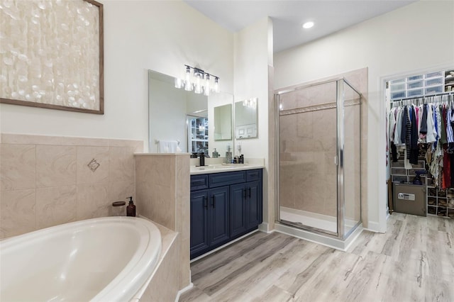 bathroom with independent shower and bath, wood-type flooring, and vanity