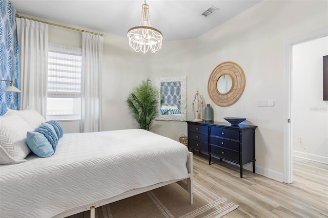 bedroom with an inviting chandelier and light hardwood / wood-style floors