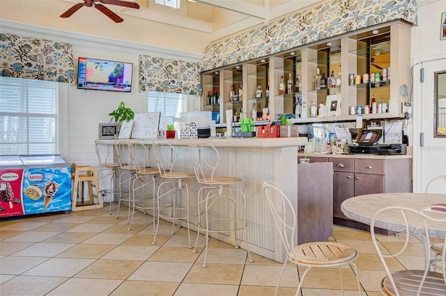 bar featuring light tile patterned floors and ceiling fan