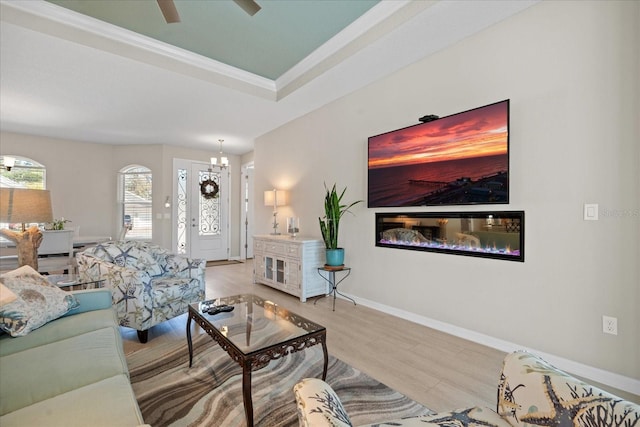 living room featuring an inviting chandelier, light hardwood / wood-style flooring, and a raised ceiling