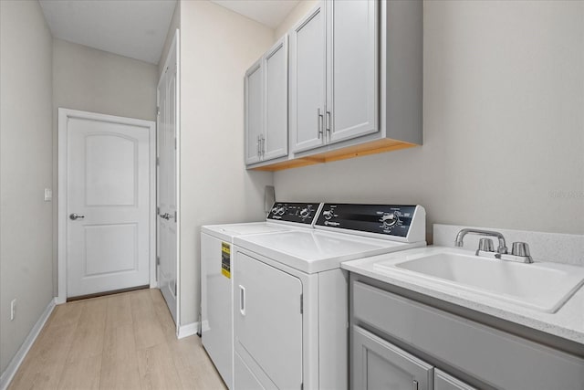 laundry room featuring cabinets, separate washer and dryer, sink, and light hardwood / wood-style flooring