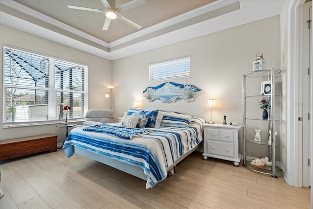 bedroom with multiple windows, ornamental molding, light hardwood / wood-style floors, and a tray ceiling