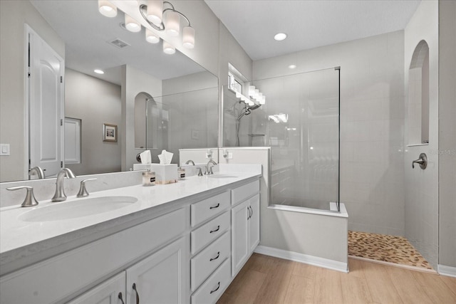 bathroom with a tile shower, vanity, and hardwood / wood-style flooring