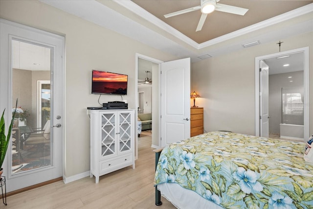 bedroom featuring light hardwood / wood-style floors, a raised ceiling, and ensuite bathroom