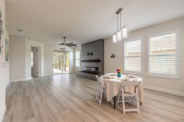 dining space with ceiling fan, a fireplace, and light hardwood / wood-style flooring