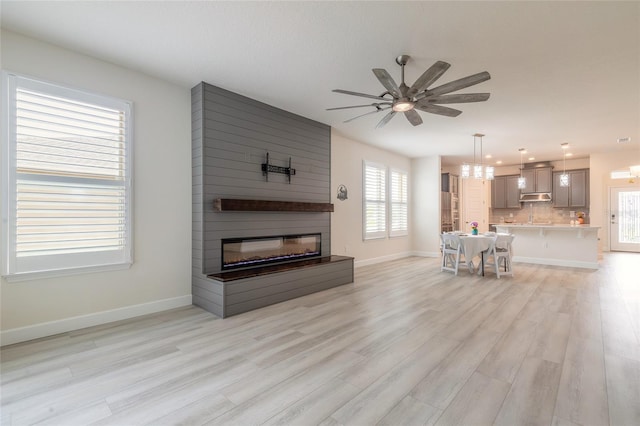 living room with ceiling fan, a fireplace, and light hardwood / wood-style floors