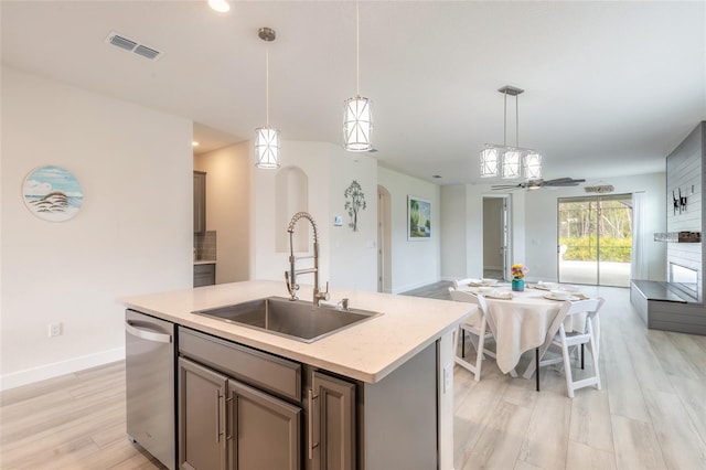 kitchen featuring sink, hanging light fixtures, a kitchen island with sink, dishwasher, and light hardwood / wood-style floors