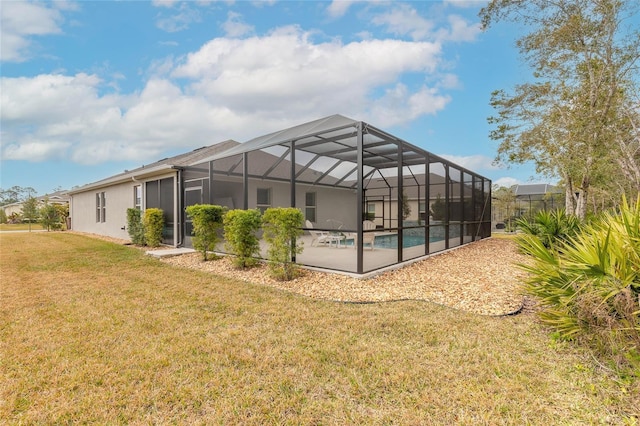 rear view of house with a yard and glass enclosure