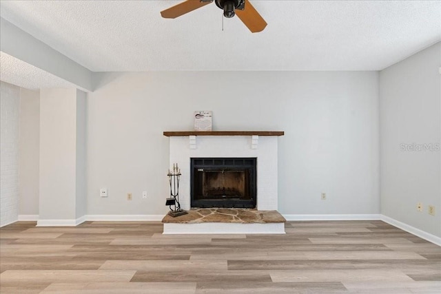 unfurnished living room with ceiling fan, a textured ceiling, and light wood-type flooring