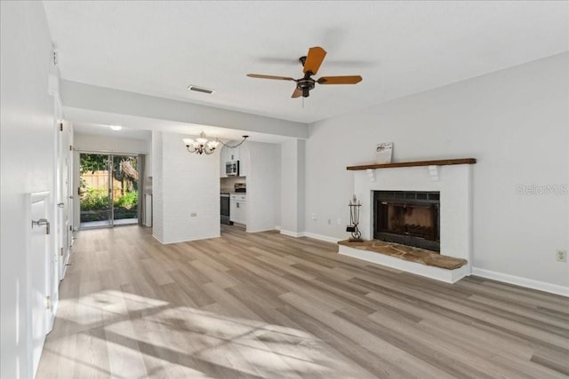 unfurnished living room with ceiling fan with notable chandelier and light wood-type flooring