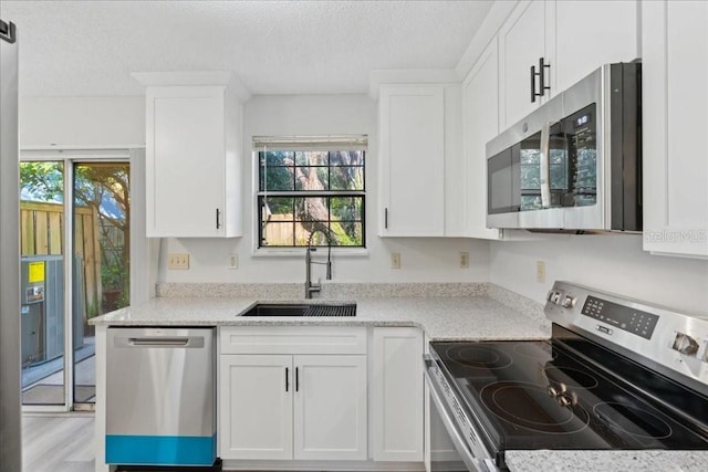 kitchen with light stone countertops, stainless steel appliances, and white cabinets