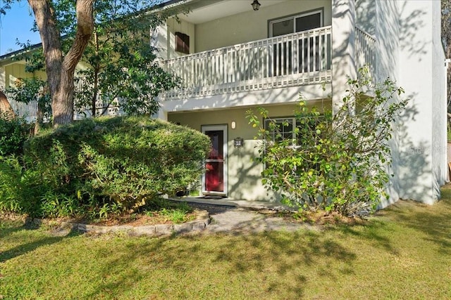 back of house featuring a lawn and a balcony