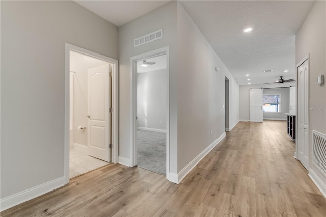 corridor with light hardwood / wood-style floors and a textured ceiling