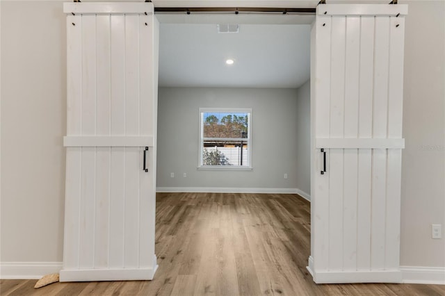 spare room with a barn door and light wood-type flooring