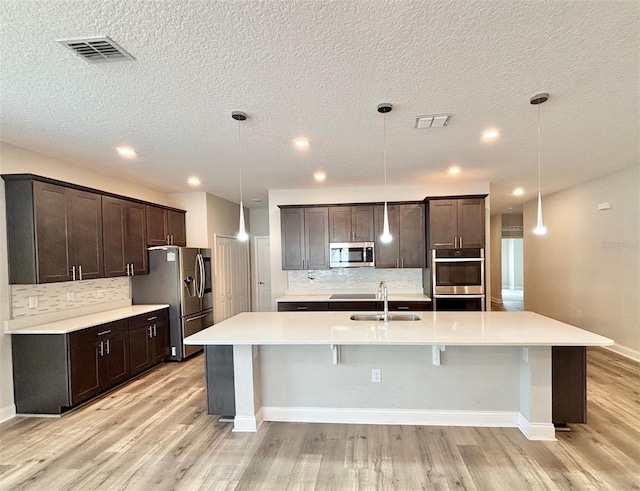 kitchen featuring pendant lighting, dark brown cabinetry, and appliances with stainless steel finishes