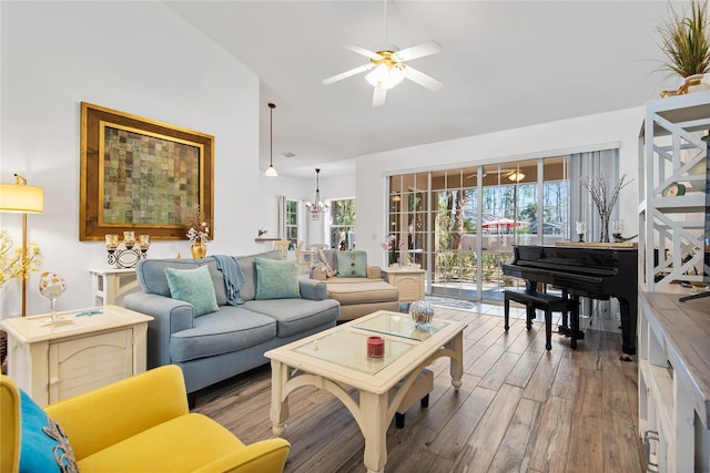 living room featuring lofted ceiling, ceiling fan with notable chandelier, and light wood-type flooring