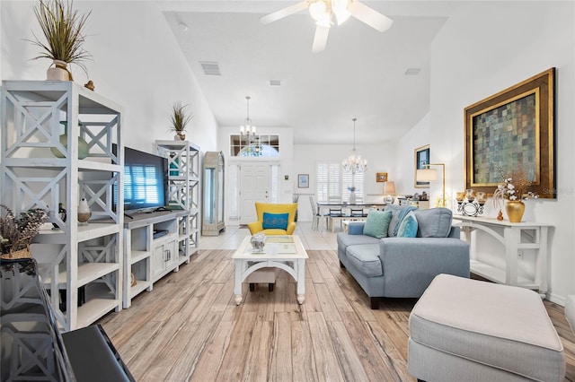 living room with ceiling fan with notable chandelier, high vaulted ceiling, and light hardwood / wood-style floors