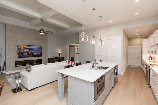 kitchen with light countertops, appliances with stainless steel finishes, a sink, and light wood-style flooring