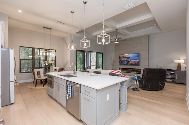 kitchen featuring coffered ceiling, freestanding refrigerator, light wood-type flooring, stainless steel dishwasher, and a sink