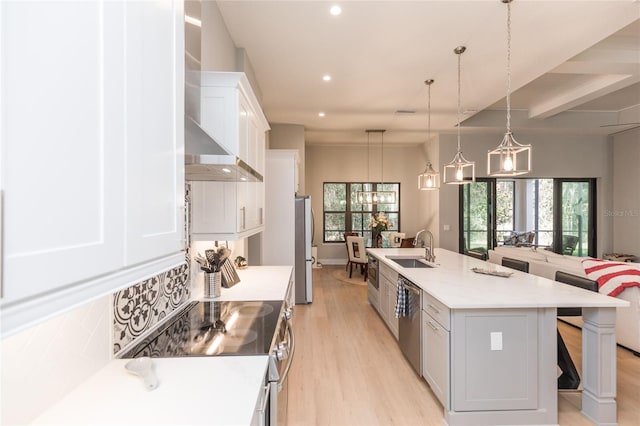 kitchen featuring a breakfast bar, light wood finished floors, stainless steel appliances, a sink, and wall chimney range hood