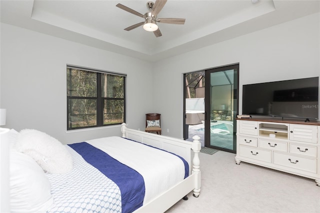 bedroom featuring access to outside, a tray ceiling, and light colored carpet