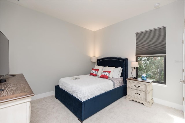 bedroom featuring light carpet and baseboards