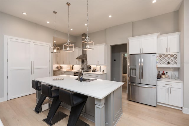 kitchen featuring decorative backsplash, stainless steel refrigerator with ice dispenser, a sink, and light wood-type flooring
