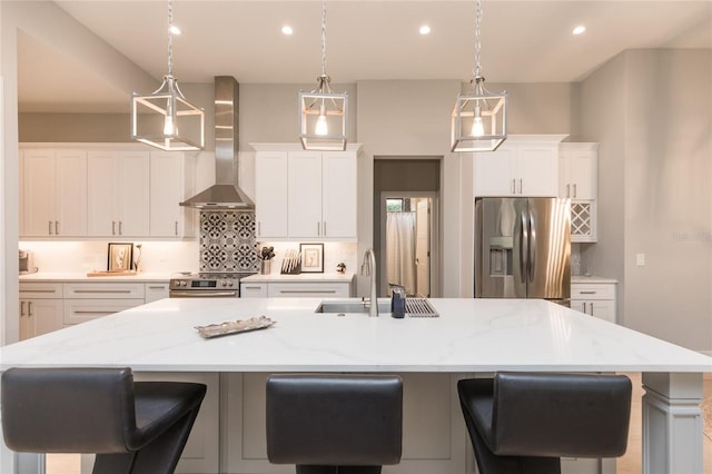 kitchen with stainless steel appliances, backsplash, wall chimney range hood, a sink, and a spacious island