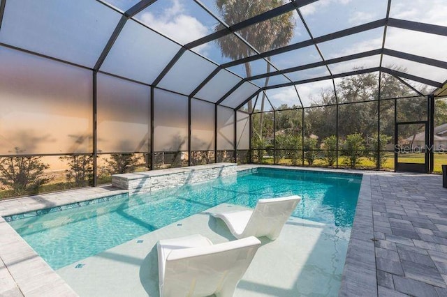 outdoor pool featuring glass enclosure and a patio area