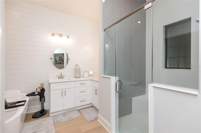 bathroom with vanity, wood finished floors, a tub, and a stall shower