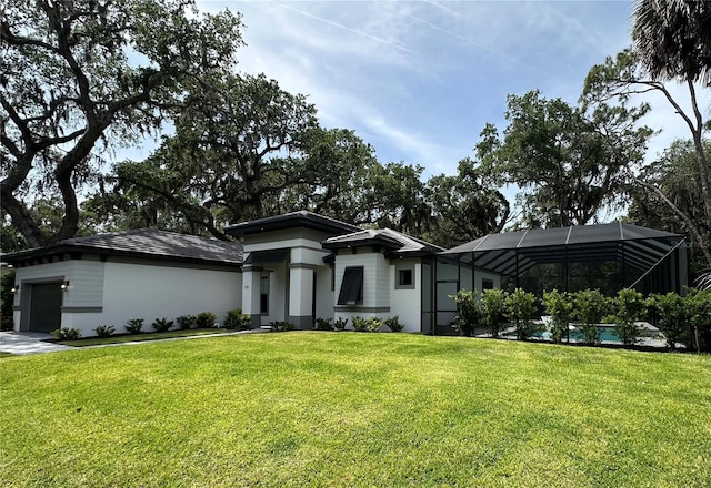 prairie-style house featuring an attached garage, glass enclosure, a front yard, and stucco siding