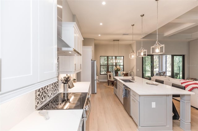 kitchen featuring wall chimney range hood, a sink, stainless steel appliances, light wood-style flooring, and recessed lighting