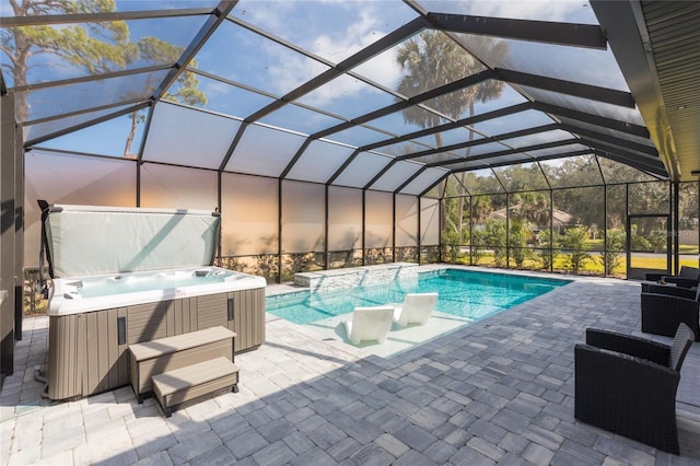 outdoor pool featuring glass enclosure, a hot tub, and a patio