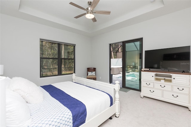 bedroom with a raised ceiling, access to exterior, light colored carpet, and ceiling fan