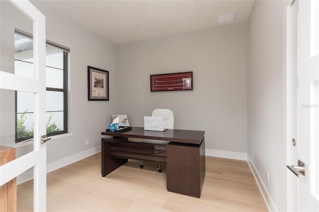 home office with visible vents, light wood finished floors, and baseboards